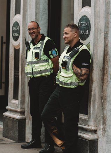 Two security guards standing outside Regent House in London, smiling and on duty.